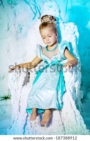 Little girl in princess dress on a background of a winter fairy tale. Baby snow queen. Sweet smiling child snowy kingdom. Kid in in carnival costume.