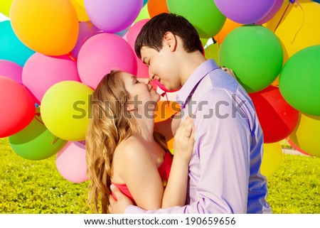 Young healthy beautiful pregnant woman with her husband and balloons outdoors. A Men  and girl with a tummy on the grass. Enjoyed by nature. Couple in love waiting for baby