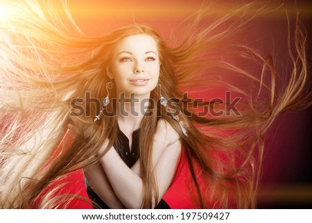 Woman with long luxury hair. Beautiful young stylish fashionable girl with flying hair in the wind