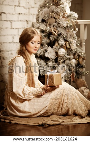 Young luxury vintage woman near Christmas tree with gift. Beautiful young girl celebrates Christmas in vintage style.