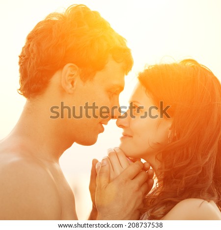 A young  loving  couple hugging and kissing on the beach at sunset. Two lovers, man and woman near the water. Summer in love