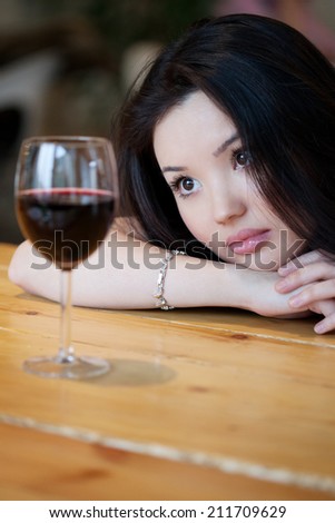 Young beautiful trendy woman in the bar. Beautiful Asian girl in a pub. Woman with alcohol.