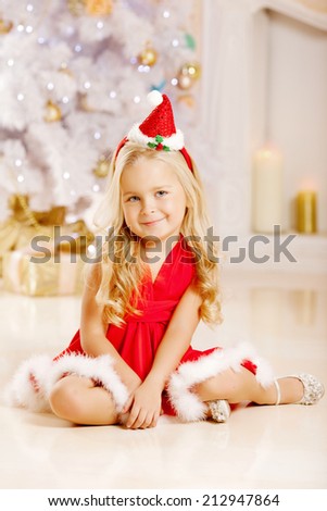 Beauty little Santa girl near the Christmas tree.  Happy girl celebrates  christmas.