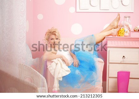 Cute woman looks like a doll in a sweet interior. Young pretty smiling girl