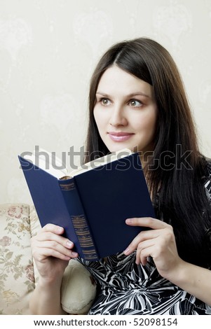 Image of a beautiful woman, who reads book  sitting on the sofa