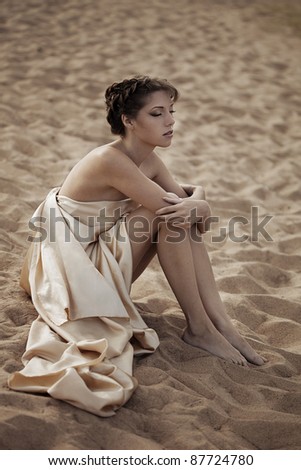 Picture of woman in flying gold cloth in the sand