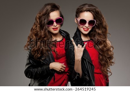 Sisters twins in hipster sun glasses laughing Two fashion models Women smiling positive Friends group having fun, talking Youthful friendship youth adults people culture concept Young girls rock party