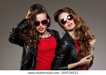 Sisters twins in hipster sun glasses laughing Two fashion models Women smiling positive Friends group having fun, talking Youthful friendship youth adults people culture concept Young girls rock party