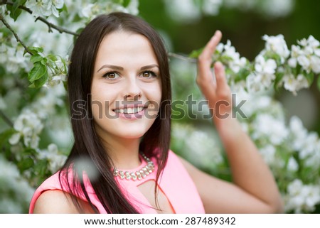 Young spring fashion woman. Trendy girl in the flowering trees in the spring summer garden. Springtime or summertime. Lady in spring landscape background. Allergic to pollen of flowers. Spring allergy