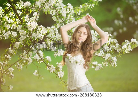 Young spring fashion woman in spring garden Springtime Summertime Trendy girl in the flowering trees in then at sunset in spring  summer landscape background Allergic to pollen of flowers Allergy
