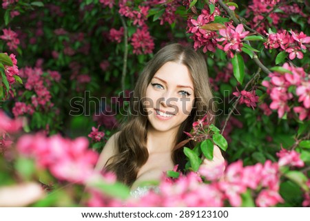 Young spring fashion woman in spring garden Springtime Summertime Trendy girl in the flowering trees in then at sunset in spring summer landscape background Allergic to pollen of flowers Allergy