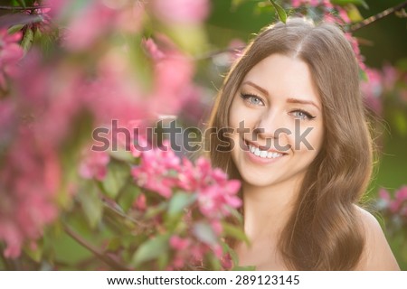 Young spring fashion woman in spring garden Springtime Summertime Trendy girl in the flowering trees in then at sunset in spring summer landscape background Allergic to pollen of flowers Allergy