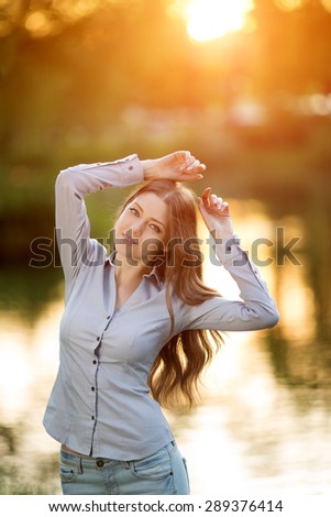 Romantic girl outdoors enjoying nature Beautiful Model in Casual jeans in sun light Long healthy Hair  Backlit Warm Color Tones Beauty Sunshine woman Smiling Sunny Summer Day Autumn Summertime Glow