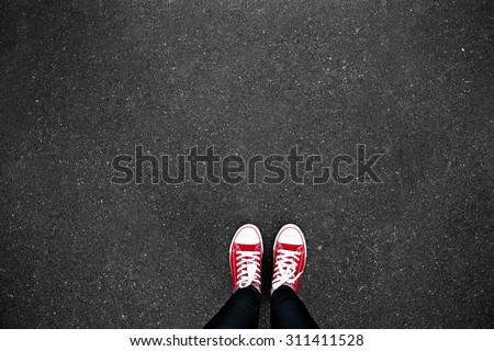 Gumshoes on urban grunge background of asphalt. Conceptual image of legs in boots on city street. Feet shoes walking in outdoor. Youth Selphie Modern hipster