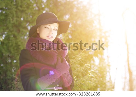 Winter woman on background of winter landscape, sun. Fashion girl in forest wonderland. Winter sunset scene. Model in sunlight, backlight