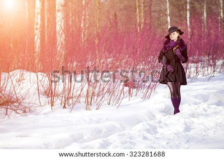Winter woman on background of winter landscape, sun. Fashion girl in forest wonderland. Winter sunset scene. Model in sunlight, backlight