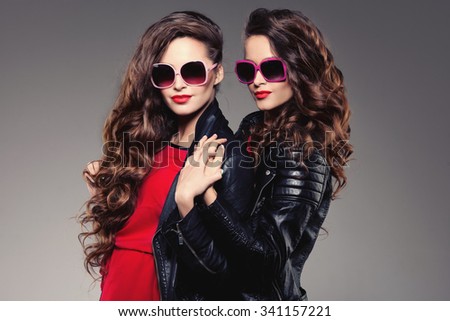 Sisters twins in hipster sun glasses laughing Two fashion models Women smiling positive Friends group having fun, talking Youthful friendship youth adults people culture concept Young women rock party