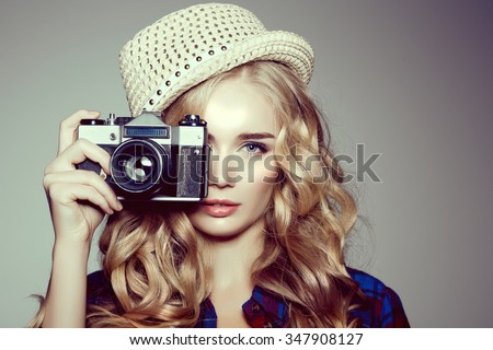 Young woman with camera. Blonde in a plaid shirt. Hipster fashion photographer girl. Young people, youth culture