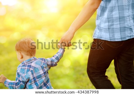 Child, baby holding an adult's hand. Father and son on a walk. The kid and the man.