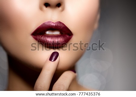 Red woman lips, mouth close up. Beautiful model girl with lipstick plum wine color. Manicure with nail polish Products Treatment