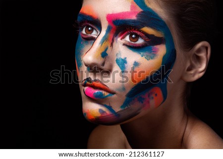 Close up portrait of a young woman with unusual makeup on a dark black background