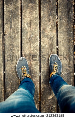 Old vintage blue shoes and legs in a blue jeans on the wooden floor