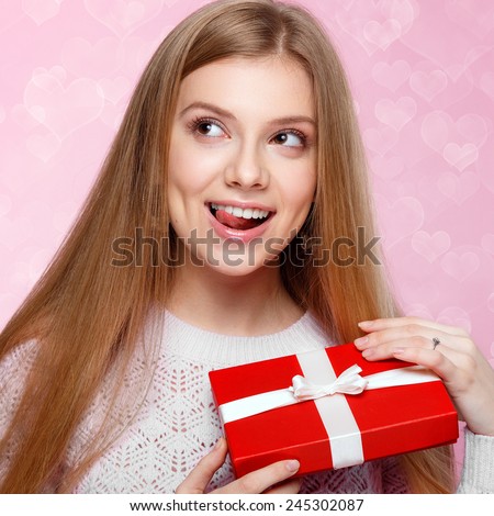 Valentines Day. Sweet blonde woman holding a gift box. heart  pink background Joyful