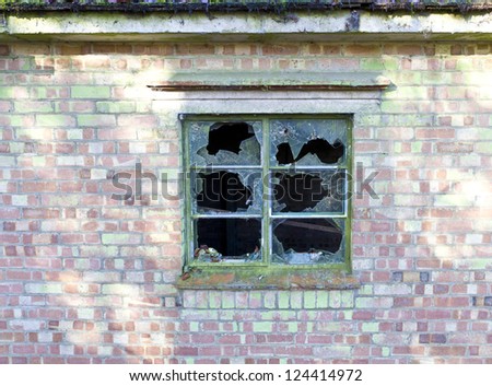 Smashed panes of glass in a window in a dilapidated old house