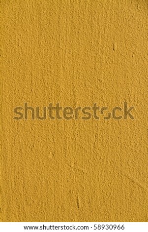 Heavily textured wall painted with bright yellow paint in close up