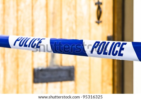 Police tape strung across a front door with shallow depth of field