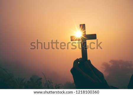 Silhouette of cross in human hand, the background is the sunrise., Concept for Christian, Christianity, Catholic religion, divine, heavenly, celestial or god.