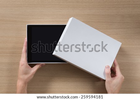 New tablet pc in white box on wooden table.