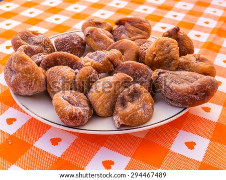 Close up of dry figs on a plate on an orange table with heart design.