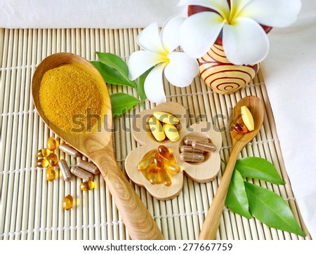 Herbal supplements and vitamins  on wooden tray and wooden spoon, decorated with white flowers and green leafs background as bamboo blinds white cotton cloth