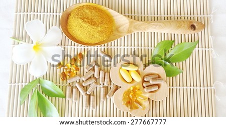 Herbal supplements and vitamins  on wooden trayand dry powder herbal inwooden spoon, decorated with white flowers and green leafsThe backdrop is the bamboo blinds