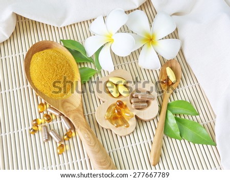 Herbal supplements and vitamins  on wooden tray and wooden spoon, decorated with white flowers and green leafs background as  bamboo blinds white cotton cloth