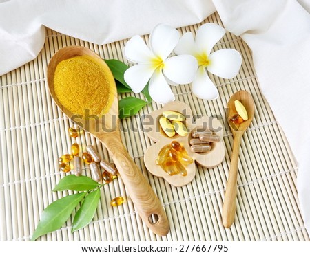 Herbal supplements and vitamins  on wooden tray and wooden spoon, decorated with white flowers and green leafs background as  bamboo blinds white cotton cloth
