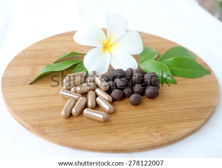 Thai herbal medicine, medicine ball lyrics Supplements in wooden tray decorated with white flower and green leaves with a white cotton background