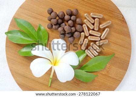 Thai herbal medicine, medicine ball lyrics Supplements in wooden tray decorated with white flower and green leaves with a white cotton background