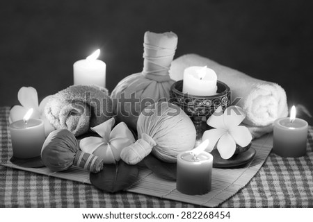 Black and white picture of  Thailand traditional medicine,\
The herbal ball for massage and spa is decorated with frangipani and candles.