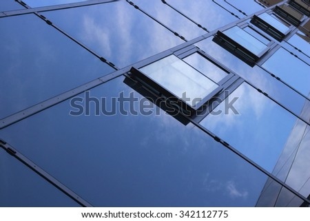 Closeup tilt photo of glass wall reflecting bright sky and clouds. Optimistic hi-tech architectural background composition with metaphorical relationship to eco-friendly technologies.