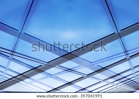 Glass architecture. Close-up photo of contemporary hi-tech architectural detail. Glazed aluminum structure wall / ceiling reflecting bright sky. Abstract background composition with ecological motif.