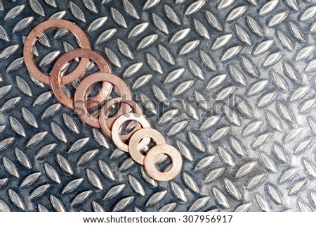 Copper washers of various sizes on a patterned metallic background.
