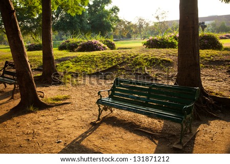 Bench in the park for people to relax on vacation. The property has a shady garden. In the evening.