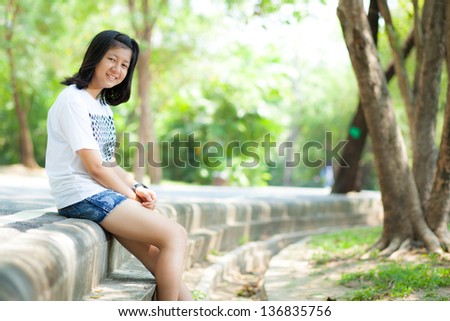 Teenage girl sitting by the road in the park.