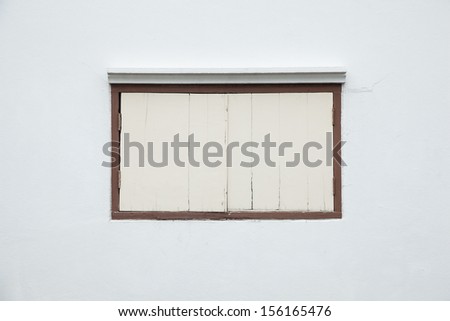 Old window on a white wall. Old white wall with a small window of the house.