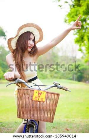 asian woman riding bikes and looking above. The hand was pointed to above it in the park.