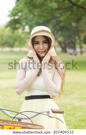 Woman holding a hat. Happy and relaxed in the relaxation area of the park.