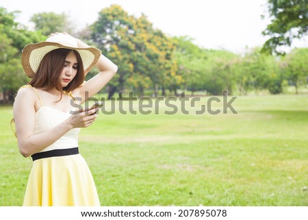 Woman play smart phones. Woman with hat standing in a park with a phone.