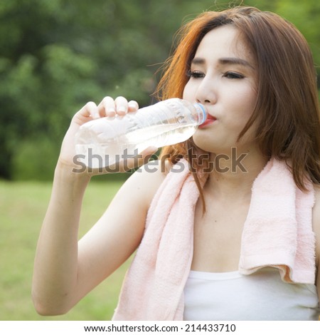 Woman standing water breaks during exercise. Jogging in the park during the evening.